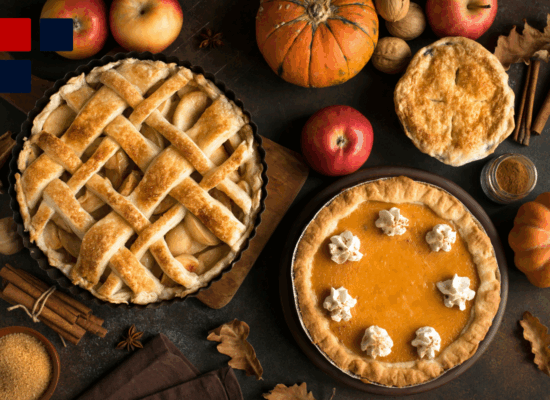 A dinner table at Thanksgiving with apple and pumpkin pie and fruit like apples and pumpkins