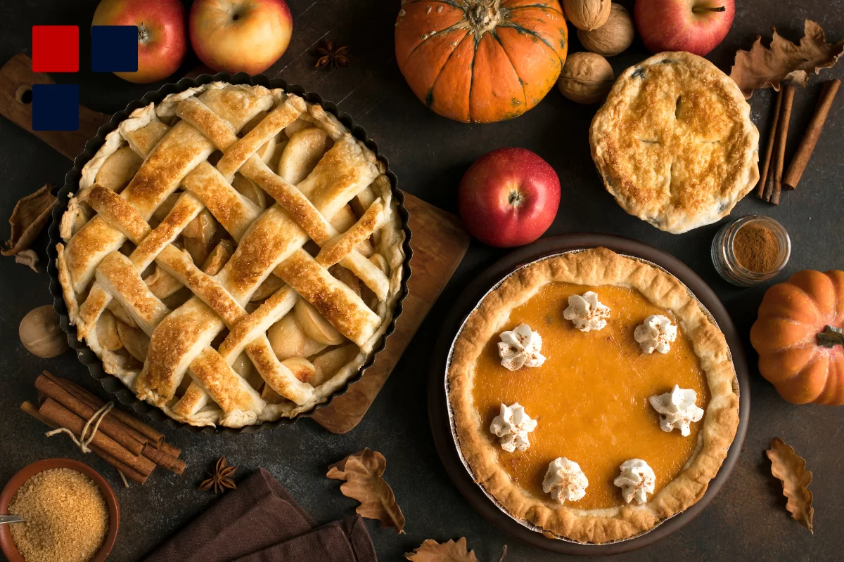 A dinner table at Thanksgiving with apple and pumpkin pie and fruit like apples and pumpkins